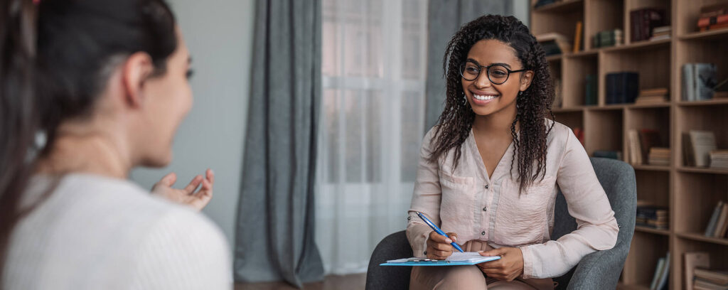 psychologist leading a therapy session and taking notes during counselling